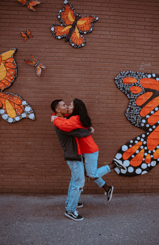Kissing couple, in front of brick butterfly wall