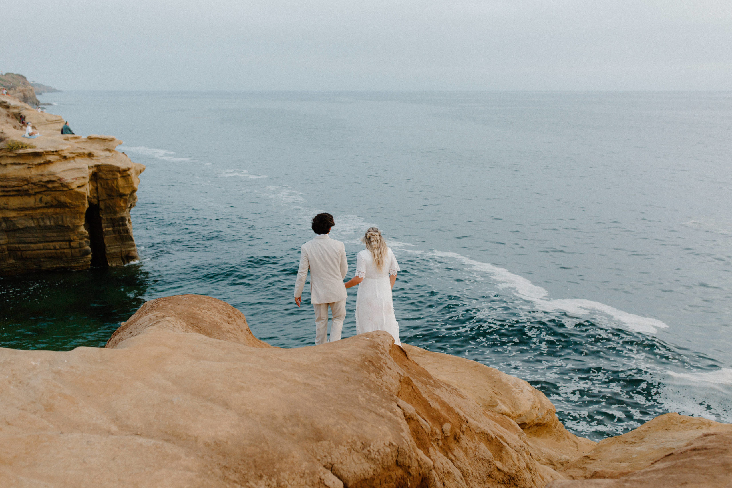 bride and groom on the edge of sunset cliffs