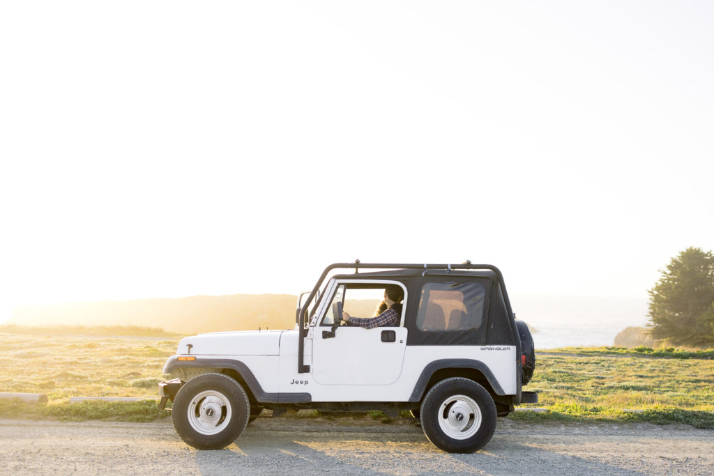 couple in a white jeep overlooking the ocean