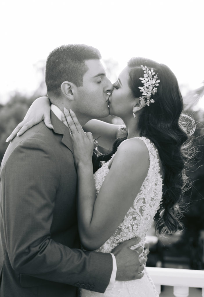 black and white of bride and groom kissing during sunset