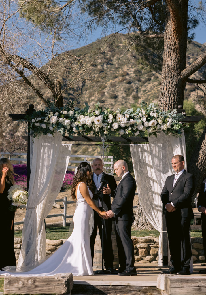 wide shot of bride and groom mid ceremony under canopy