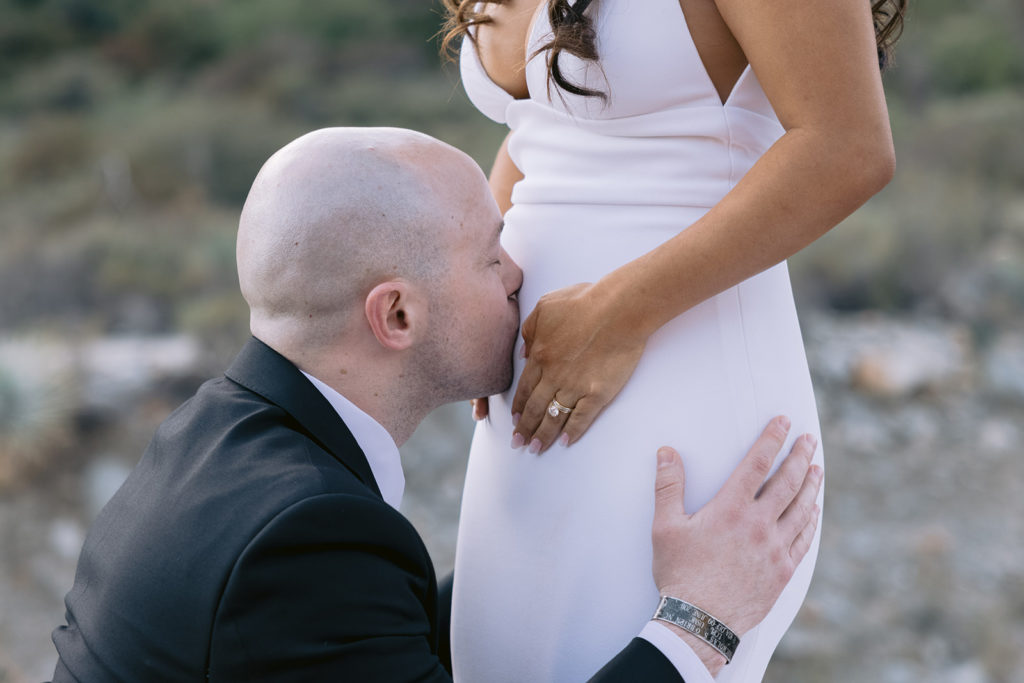 groom kissing bride's pregnant belly