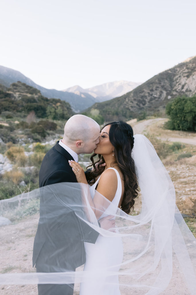 bride and groom kiss in the mountains