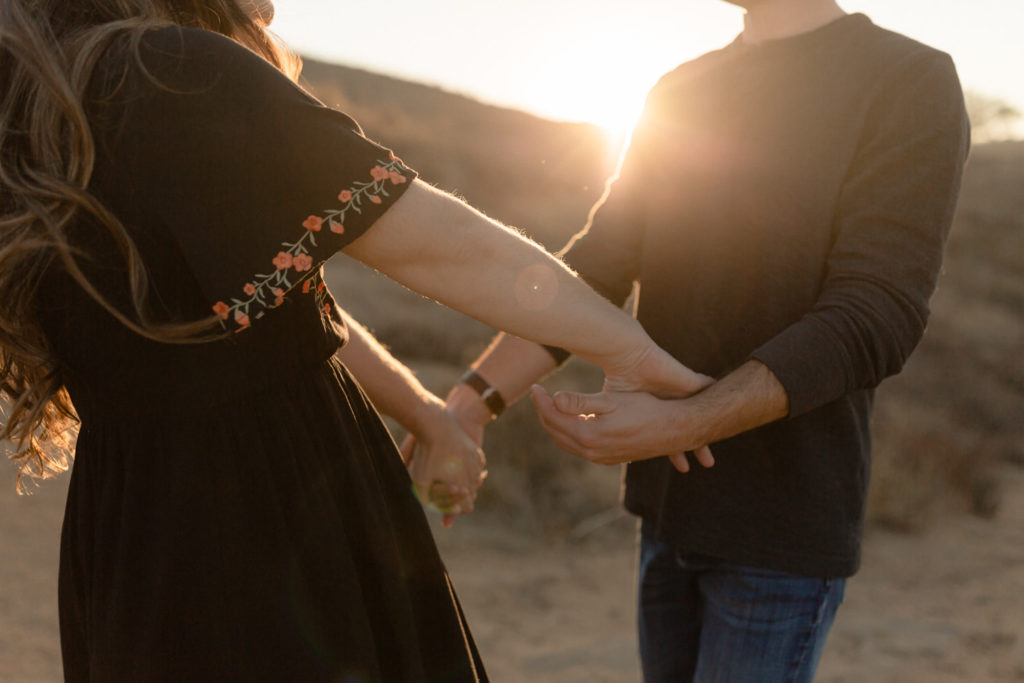 couple holding hands at engagement session during sunset