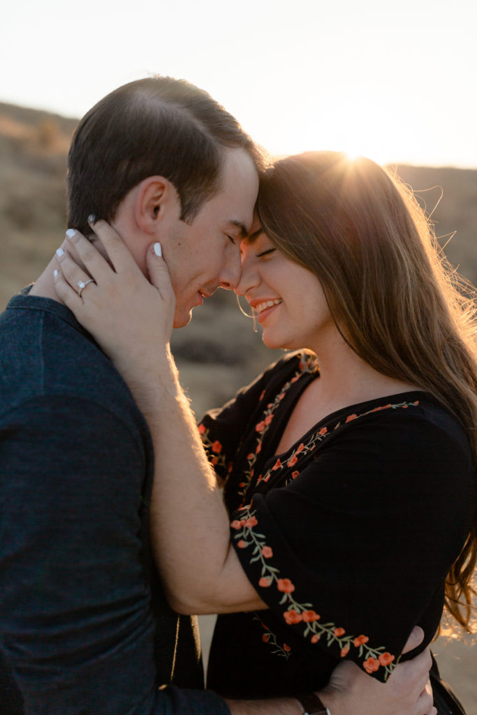 couples smiling with their faces close together at sunset